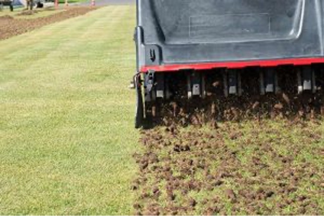 A lawn aerator machine in action, perforating grass to improve soil aeration and promote healthier lawn growth, with visible before-and-after effects.